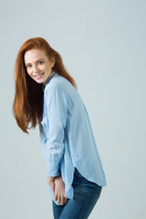 beautiful young smiling girl with red hair on a light background