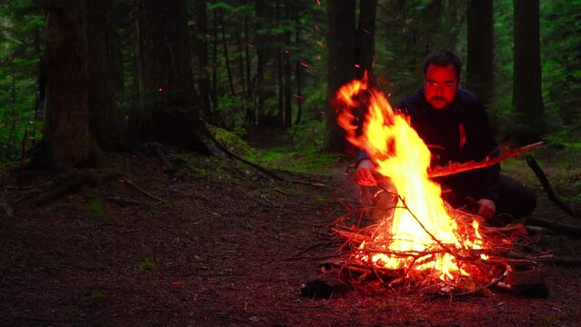 Young man camper sitting by the campfire. slow motion video