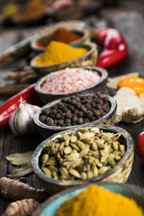 A selection of various colorful spices on a wooden table in bowls