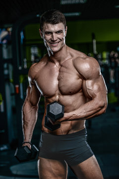 Handsome model young man training arms in gym