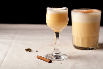 Two glasses with christmas eggnog drink decorated with cinnamon on dark background. Horizontal composition with copy space.