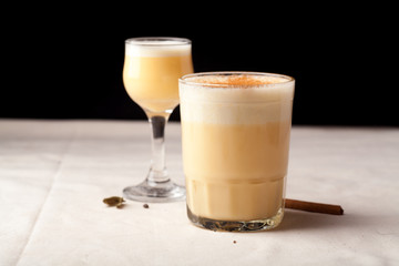 Two glasses with christmas eggnog drink decorated with cinnamon on dark background. Horizontal composition with copy space.