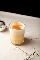 Two glasses with christmas eggnog drink decorated with cinnamon on dark background. Vertical composition.