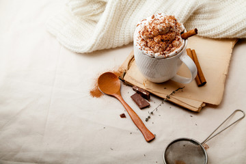 Cup of cocoa with cinnamon, whipped cream and chocolate. Textile background. Scandinavian winter concept. Horizontal composition with copy space.