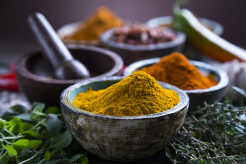 A selection of various colorful spices on a wooden table in bowls