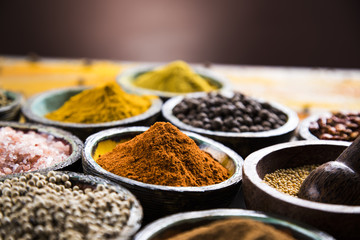 A selection of various colorful spices on a wooden table in bowls