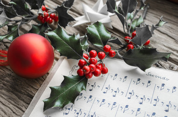 Altes handgeschriebenes Notenblatt mit Ilex Zweig, roten Beeren und roter Weihnachtskugel,...