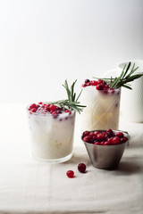 Perfect christmas cocktail: coconut margarita with cranberries and rosemary. Minimalistic concept. Linen cloth and white background. Vertical composition with copy space.