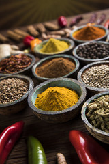 A selection of various colorful spices on a wooden table in bowls