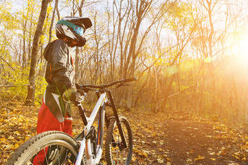Portrait of a young rider in full protection of a full face helmet mask and gloves on a bicycle
