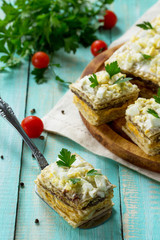 Snack cake on waffle cakes with herring pate, mushroom pate and cheese-egg cream on a kitchen wooden table.