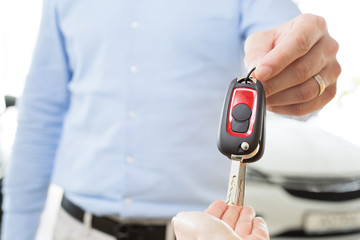 male adult dealer hand giving car keys to female person, close-up photo