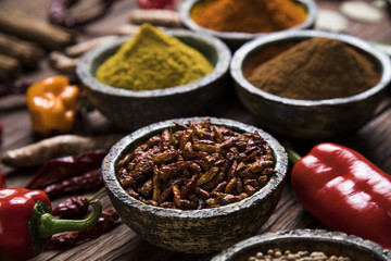 A selection of various colorful spices on a wooden table in bowls