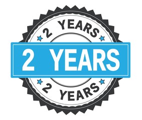 2 YEARS text on grey and cyan round stamp, with zig zag border.