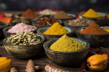 A selection of various colorful spices on a wooden table in bowls