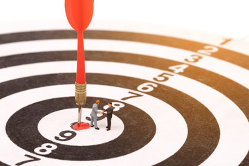 miniature people on dartboard and shaking hand,business concept