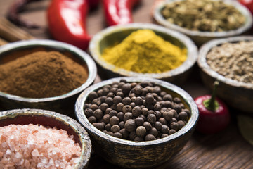 A selection of various colorful spices on a wooden table in bowls
