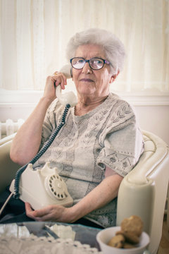 Senior Woman Talking On Landline Telephone At Home.