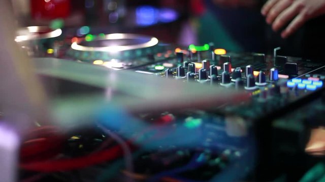 DJ plays music mixing and scratching on turntable music equipment. Professional music equipment with lights and controls being played by male disc jockey. 1920x1080