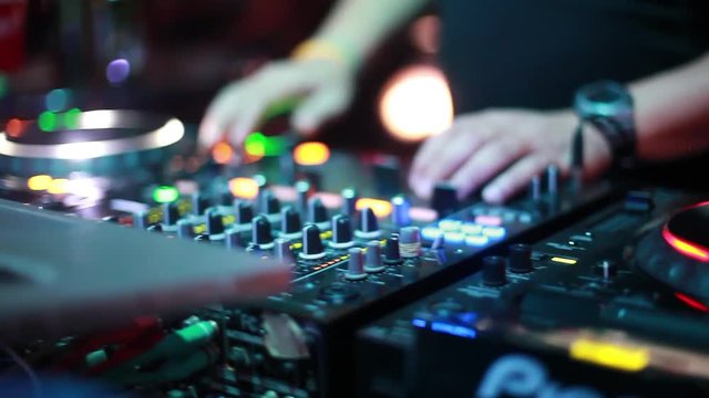 DJ plays music mixing and scratching on turntable music equipment. Professional music equipment with lights and controls being played by male disc jockey. Close up. 1920x1080