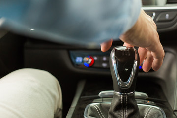 Male adult person sitting inside a new modern car, close up of hand changing a