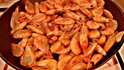 Delicious medium-sized shrimps with the heads fried on a pan with garlic and spices
