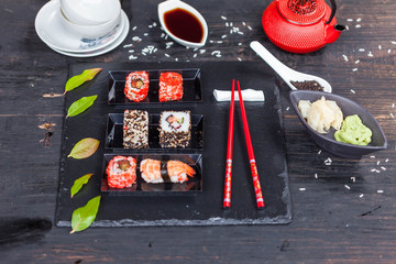 Red teapot, green leaves, slate tray and red chopsticks on old wooden table, asian background, top view, healthy wood and diet concept