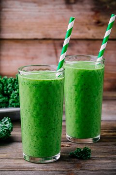 Healthy detox green smoothie with kale in a glass on wooden background