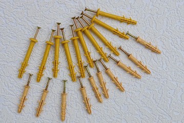 жёлтые шурупы и дюбеля в куче на серой поверхности