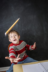 Young bored boy throwing his pencil in the air