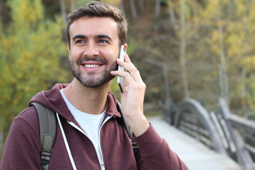 Handsome male calling by phone outdoors 
