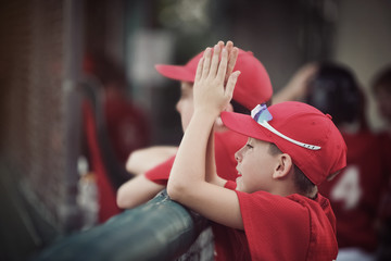 Baseball team in the dugout, cheering for their team, shallow focus, focus on hat