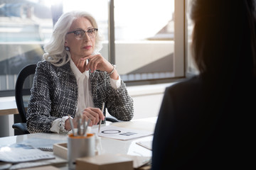 Confident senior lady is laboring with her young colleague