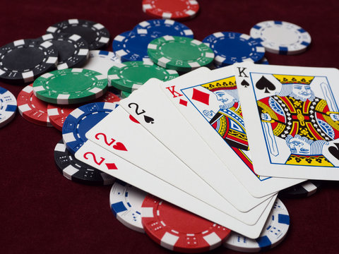 Cards and poker chips on a red background. A strong hand of Full House and a lot of chips.