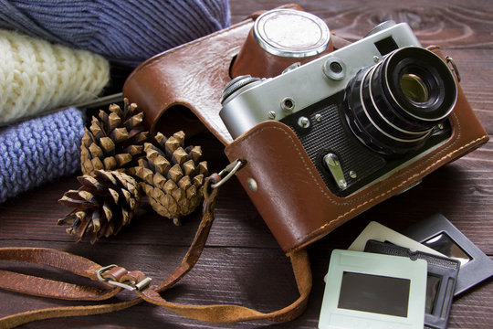 Retro camera, slides,  pine cones and hand knitted clothes.Winter and Autumn background.Nostalgia memories