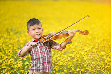 asian boy playing violin in yellow flower garden