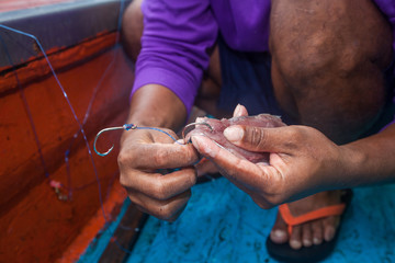 fisherman is doing hook bait for fishing on fishing boat