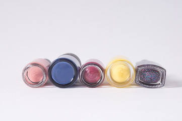 Obraz na płótnie Canvas many colored bottles of nail polish in a row, closeup on white background bottom view
