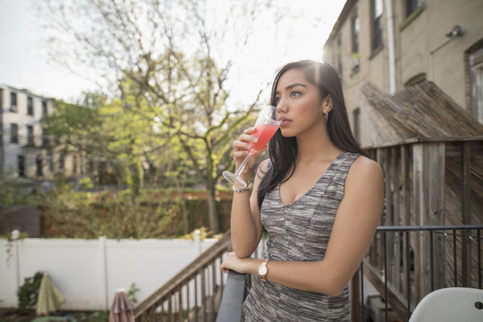 Young woman with a cocktail on her balcony