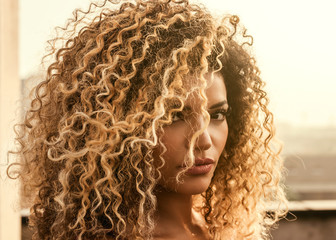 Beautiful woman with gorgeous curly hair in the sunlight