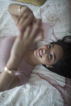 Young woman using her Smartphone on her bed