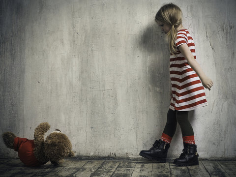 The wicked girl threw a toy bear. Background textured wall. The concept of children's resentment, the complexity of education, the child's behavior