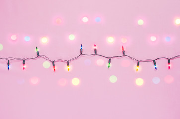 Christmas lights bulbs on string with bokeh light in red, blue & green colour on pink background with copy space for Xmas text decor, new year or special event celebration (pine tree ornament concept)