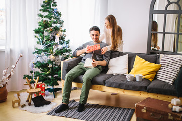 Young couple with gifts in front of Christmas tree