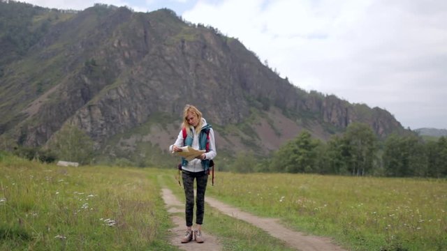 girl traveler with a map on the background of mountains