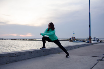 young woman do stretching exercises, sunrise in sea background  