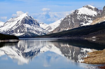 Many Glaciers snow covered mountain and landscape reflecting off of Swiftcurrent lake in Montana, USA © Cheryle