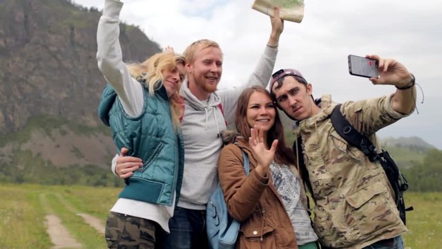 friends travelers with backpacks do selfie on the phone in the mountains