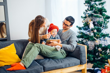 family sitting in living room having fun with tablet that Santa Claus brought