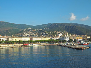 Fototapeta premium FRANCE, CORSE, BASTIA, JUNE 23, 2017: View from sea on Bastia port and surrounding hills and blue sky background